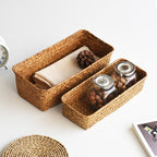 Small narrow rectangular woven baskets holding napkins and jars