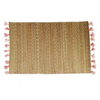 Rectangular hand woven straw placemat with pink cotton tassels at the edges