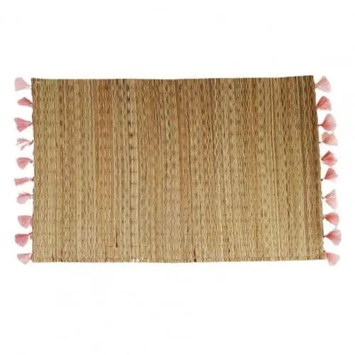 Rectangular hand woven straw placemat with pink cotton tassels at the edges