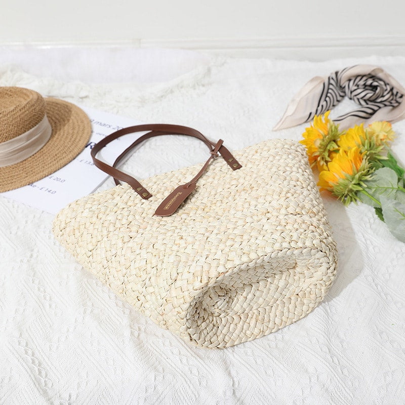Sand toned woven straw tote with two brown knotted handles