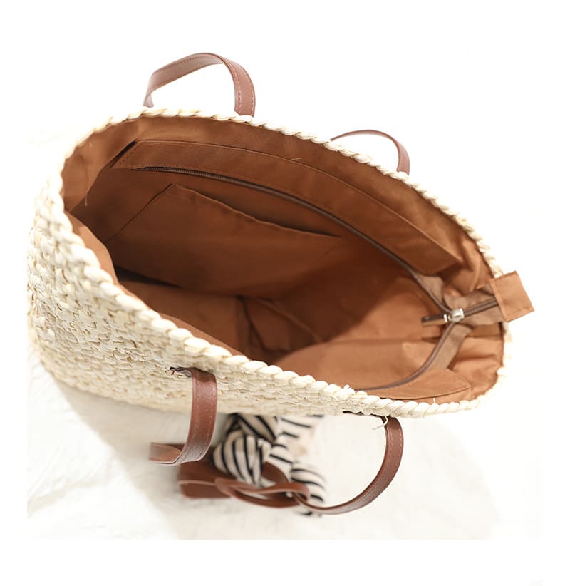 Sand toned woven straw tote with two brown knotted handles