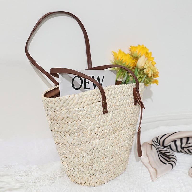 Sand toned woven straw tote with two brown knotted handles
