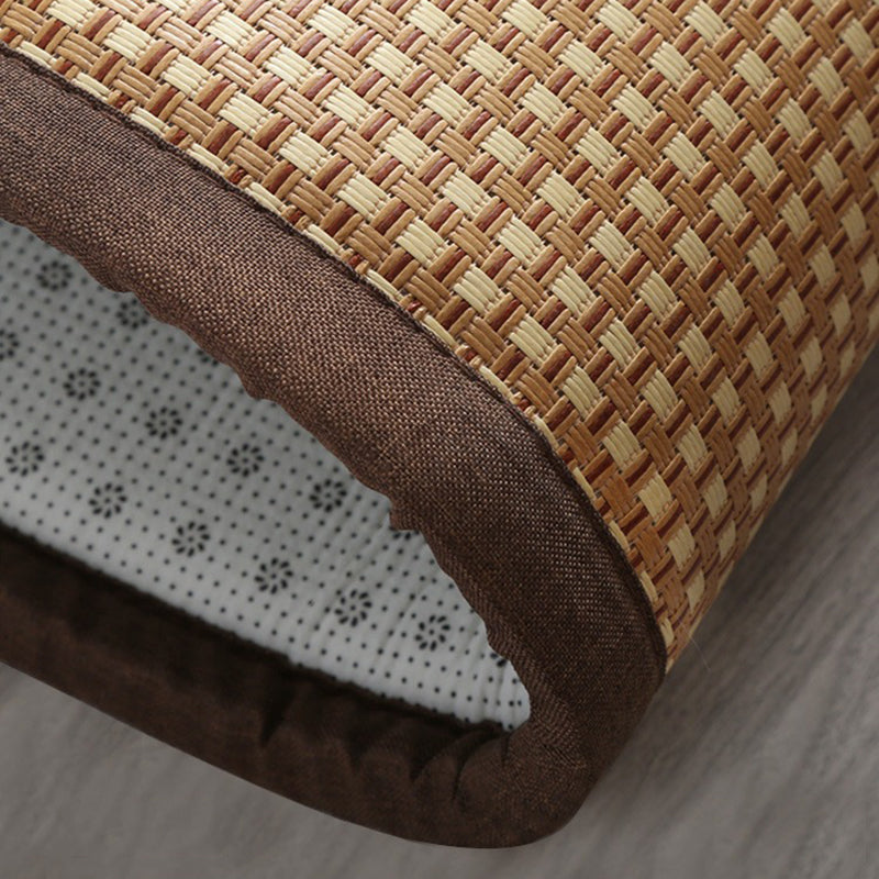 Synthetic rattan rug with a brown border beside a bed