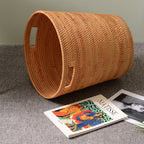 Tall honey rattan laundry basket with a towel draped over the rim