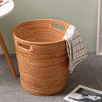 Tall honey rattan laundry basket with a towel draped over the rim