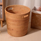 Tall honey rattan laundry basket with a towel draped over the rim