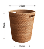 Tall honey rattan laundry basket with a towel draped over the rim