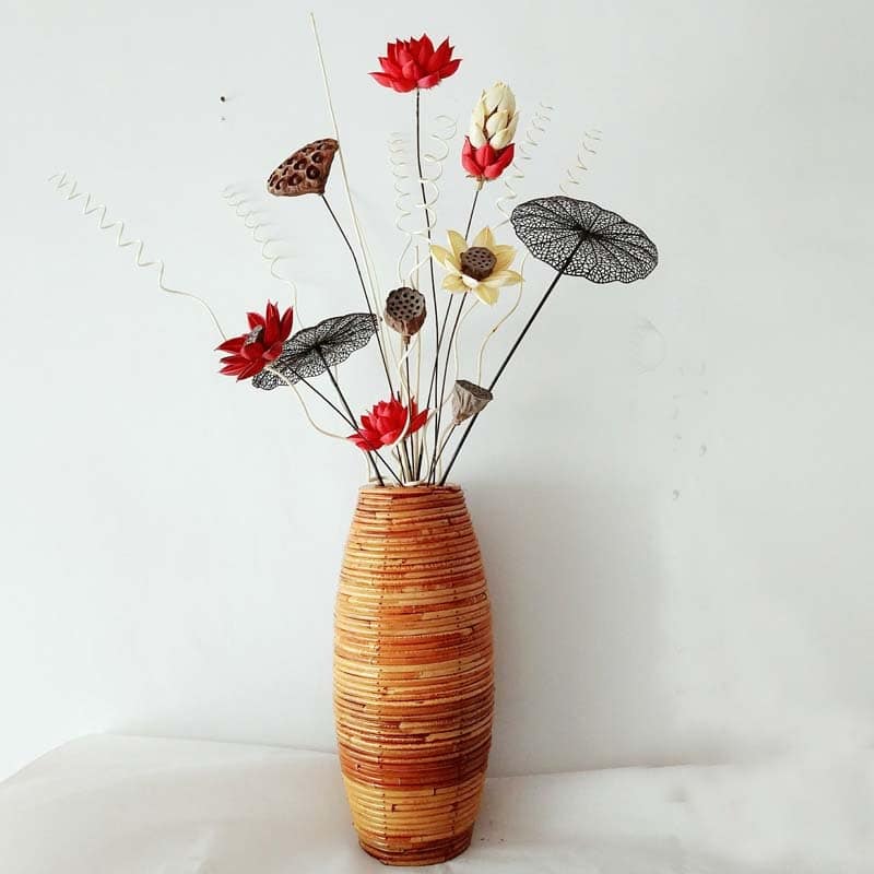 Tall bamboo floor vase with warm striped tones holding dried flowers