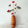 Tall bamboo floor vase with warm striped tones holding dried flowers