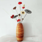 Tall bamboo floor vase with warm striped tones holding dried flowers