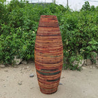 Tall bamboo floor vase with warm striped tones holding dried flowers