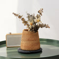 Small tapered woven rattan basket holding dried flowers