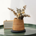 Small tapered woven rattan basket holding dried flowers