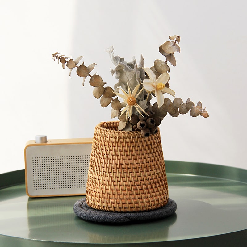 Small tapered woven rattan basket holding dried flowers