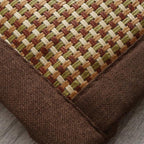 Synthetic rattan rug with a brown border beside a bed