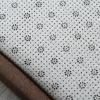 Synthetic rattan rug with a brown border beside a bed