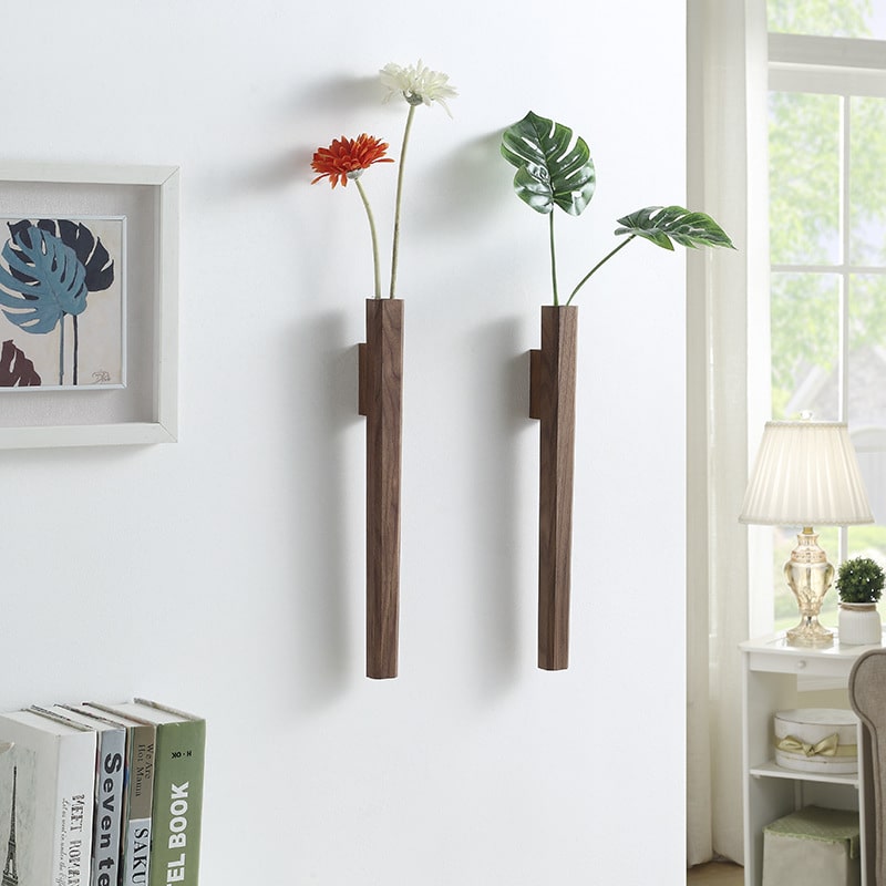 Two slim walnut wall vases holding single flowers