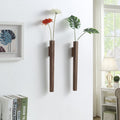 Two slim walnut wall vases holding single flowers