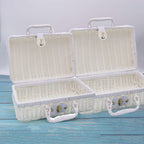 Small white woven rattan box shaped like a retro suitcase with straps