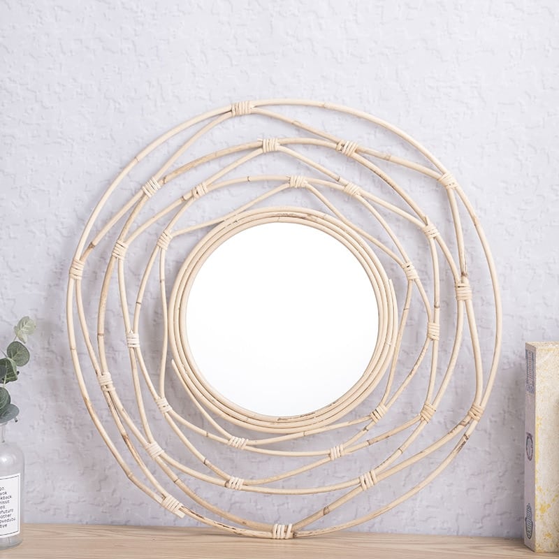 Round mirror framed by white rattan swirling loops