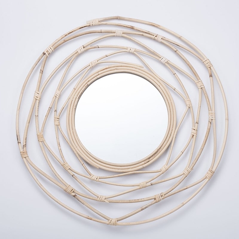 Round mirror framed by white rattan swirling loops