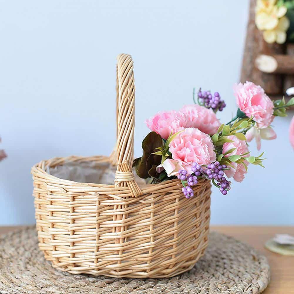 Round white wicker basket with tall handle holding pine cones