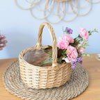 Round white wicker basket with tall handle holding pine cones