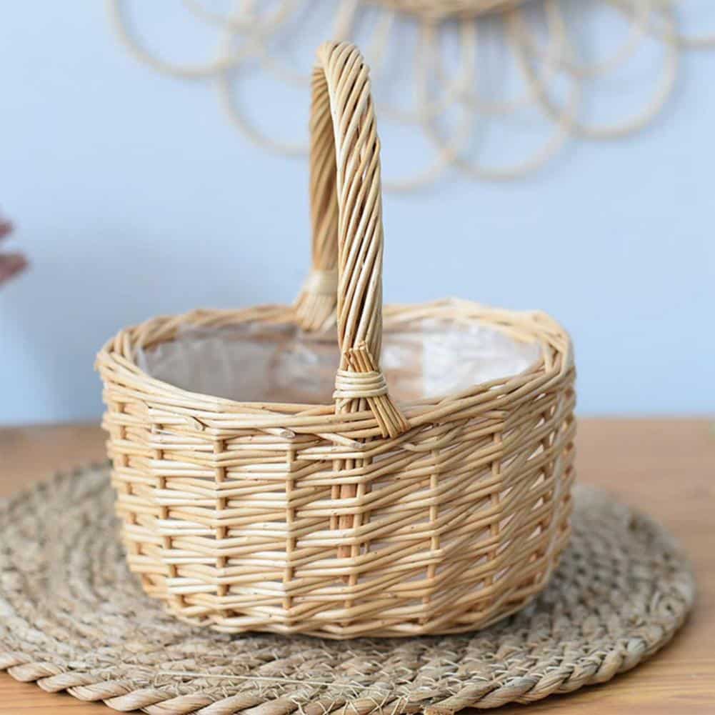 Round white wicker basket with tall handle holding pine cones