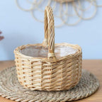 Round white wicker basket with tall handle holding pine cones