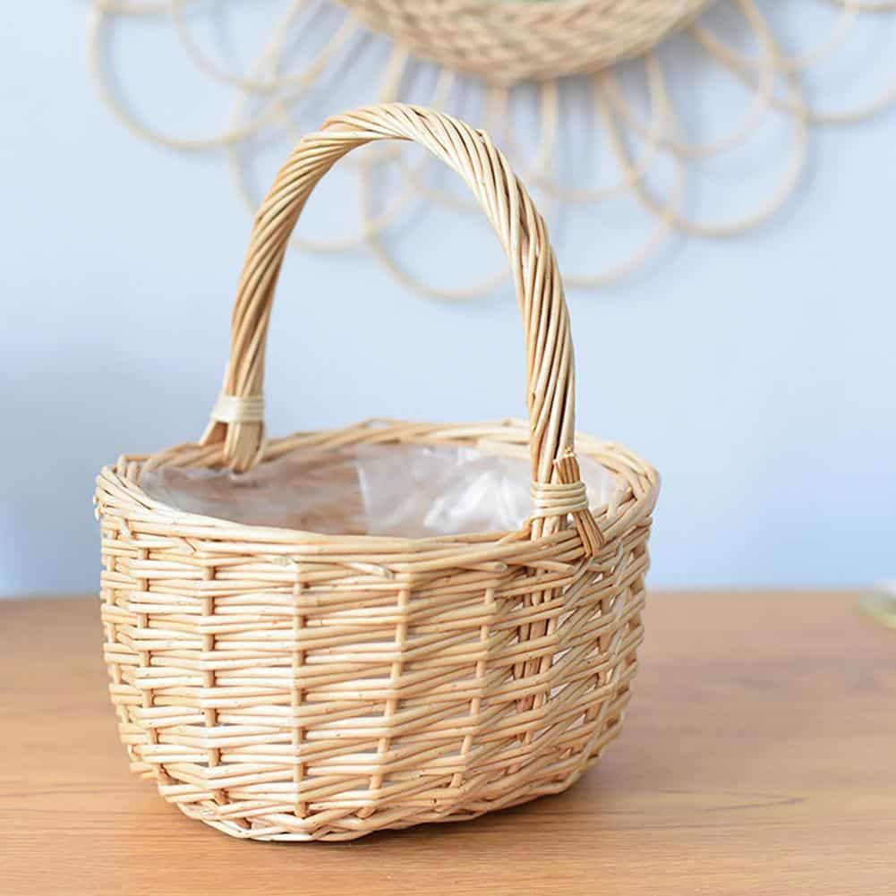 Round white wicker basket with tall handle holding pine cones