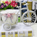 White woven tricycle holding a basket of faux flowers