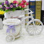 White woven tricycle holding a basket of faux flowers