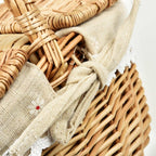 Oval wicker basket with flip lid and lace liner on a garden bench