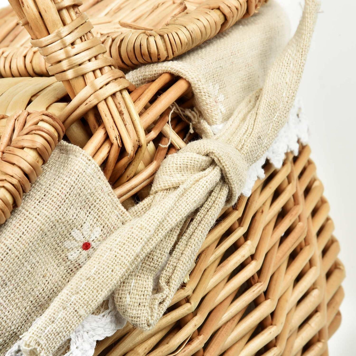 Oval wicker basket with flip lid and lace liner on a garden bench