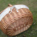 Oval wicker basket with flip lid and lace liner on a garden bench