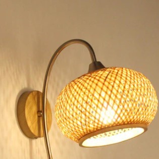 Wall sconce with woven globe shade on a curved metal arm