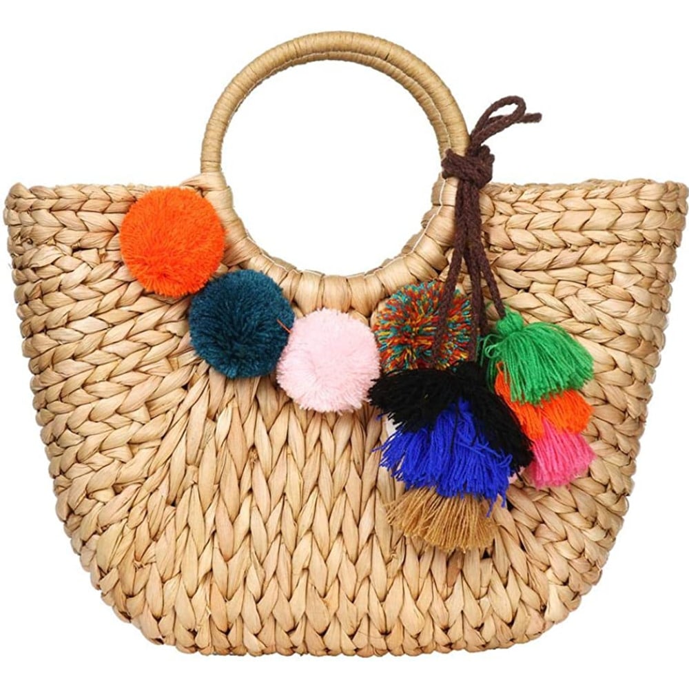 Hand woven basket bag with a round rigid handle and a cascade of colorful pompoms