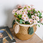 Woven belly basket with green and white tassels holding flowers