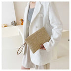 Compact beige woven clutch with a brown shoulder and wrist strap