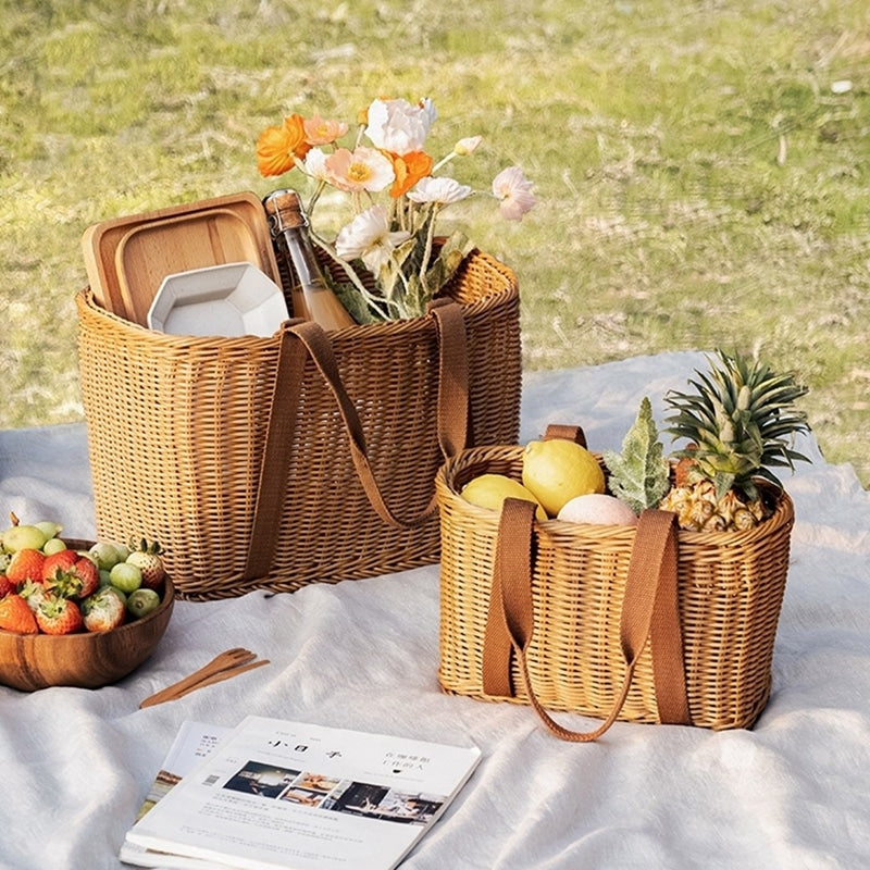Two woven picnic tote baskets with soft handles on a picnic blanket