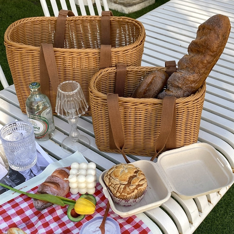 Two woven picnic tote baskets with soft handles on a picnic blanket