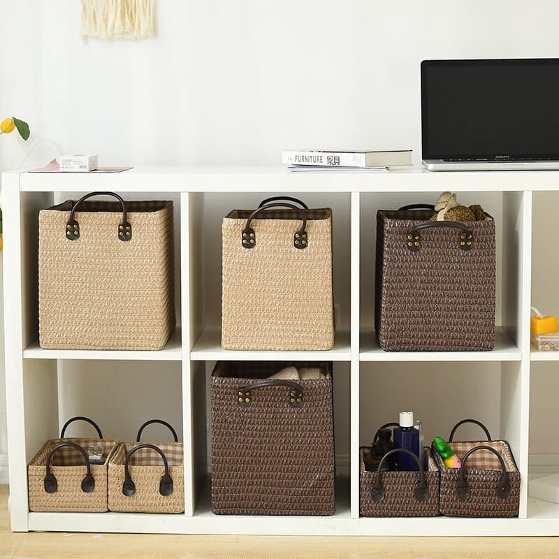 Woven storage boxes with leather look handles on a shelf