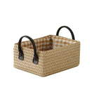 Woven storage boxes with leather look handles on a shelf