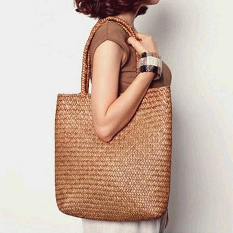 Woman carrying a large woven straw shoulder tote bag