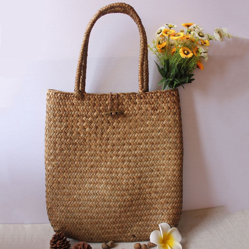 Woman carrying a large woven straw shoulder tote bag