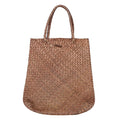 Woman carrying a large woven straw shoulder tote bag