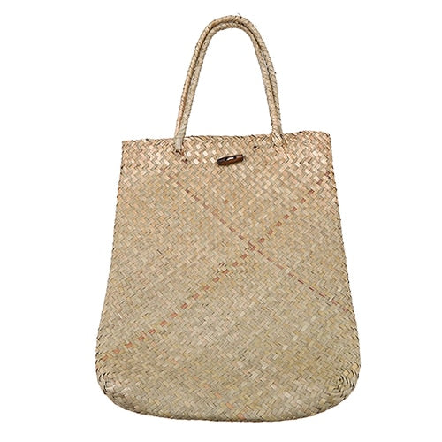 Woman carrying a large woven straw shoulder tote bag
